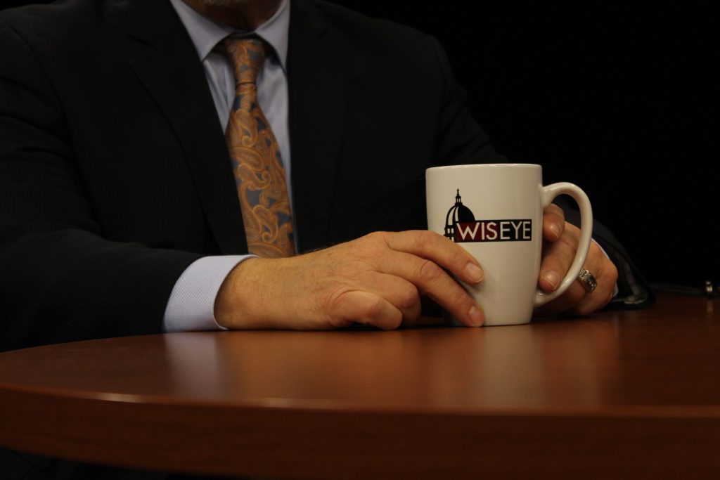 Man holding Wis Eye coffee mug